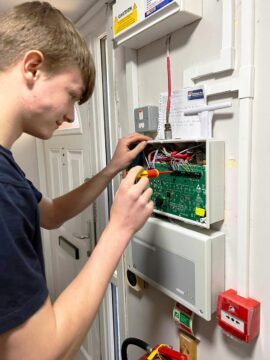 Electrotechnical Apprenticeship 1st Year Charlie working on a fire alarm control panel